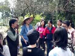 Jane talking to students wearing a traditional Chinese hat
