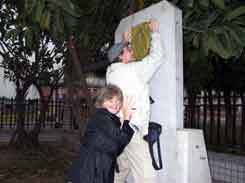 Jane holding Tim up to put paper on monument