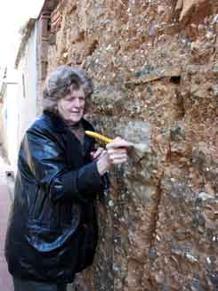 Jane brushing paper on wall in old village